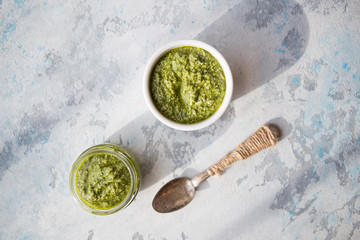 Vegetarian basil, garlic and walnut pesto. Close up of jar of homemade basil pesto with  garlic.