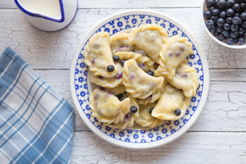 blueberry dumplings, pierogi, vareniki in a clay bowl on a old kitchen table, view from above, flat...