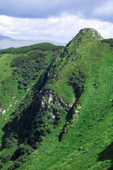 Fototapeta na wymiar green mountain alps ridge, low gray clouds