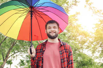 Handsome man with colorful umbrella outdoors