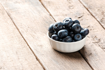 Delicious blueberries in small bowl on wooden table. Close up