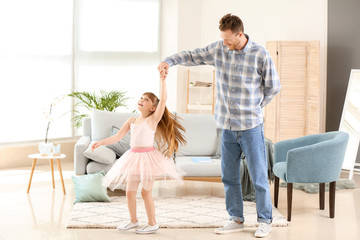 Happy father and his little daughter dancing at home