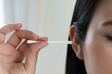 woman cleaning ear with cotton swab. Healthcare and ear cleaning concept