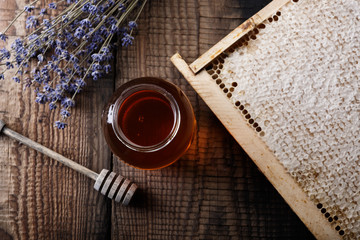Honey in a glass jar and honeycombs on an old wooden table.