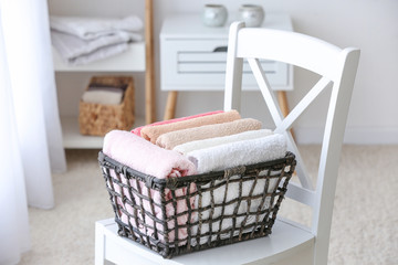 Fototapeta na wymiar Basket with clean soft towels on chair in bathroom