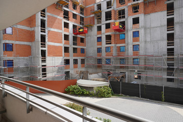 construction of monolithic high-rise apartment building. use of concrete and red bricks in construction, installation of Windows, plaster, putty, construction of walls and load-bearing structures.