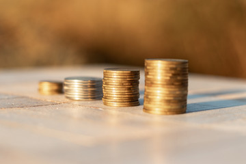 Stacks of coins laying down on the table on the beautiful sunset background, economy growth and strategy concept