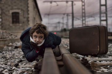 Niño posando en la via de una estacion de tren