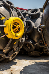 Fototapeta premium A huge Marine Pneumatic heavy rubber fender surrounded by tires fixed with chains.