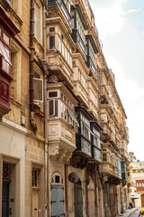 Fototapeta na wymiar street with traditional balconies and old buildings in historical city Valletta Malta