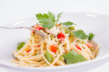 Spaghetti with cream sauce with smoked mackerel, peas ,bell pepper and some parsley eaten with a fork