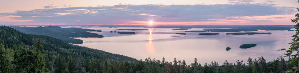 Very wide panorama view of sunrise behind lake Pielinen at summer in Koli National Park, Finland