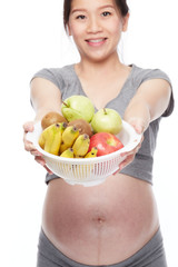 A portrait of a Happy pregnant woman with a bowl of fruits