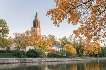 Obraz premium Beautiful fall foliage and Aura river against clear blue sky with Turku Cathedral in background in Turku, Finland, Autumn 2018