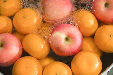 Hands washing fresh orange and apple.