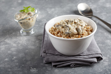 Buckwheat and quinoa porridge served with mushrooms in white vegan sauce. Healthy vegetarian food concept.