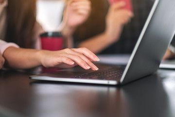 Closeup image of a woman's hand using and typing on laptop computer keyboard on the table