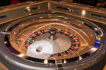 Roulette table in casino, with many games and slots, roulette wheel in the foreground. Golden and...