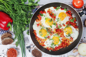 Shakshouka with five cooked eggs on top of tomato sauce in cast iron skillet
