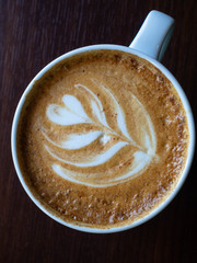 Close up hot cappuccino coffee cup with heart shape latte art on wood table at cafe, tone filter