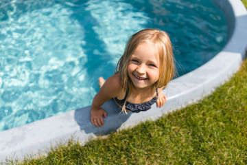 Cheerful girl in swimsuit smiling in the pool outdoors