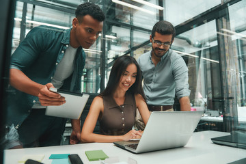 Business people. Group of three young and cheerful employees using modern technologies while...