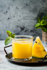 Glass of fresh golden watermelon juice or smoothie with slices of watermelon. Refreshing cold...