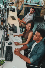 Sharing new ideas. Top view of multi ethnic team working on computers and communicating with each...