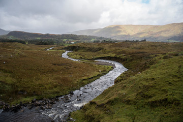 Connemara valley, river, hills and cloudy sky, Ireland