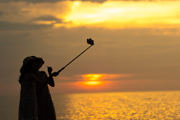 two asian woman talking a selfie using a monopod at the sea