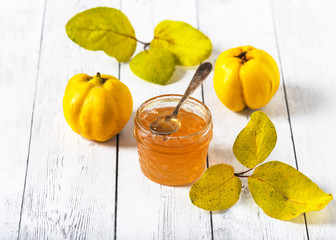 Jar of homemade quince jam with fresh quince fruit on white background. Selective focus. Copy space.