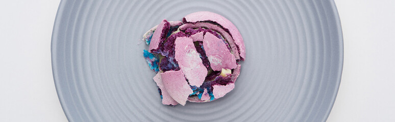 top view of delicious purple smashed French macaroon on plate isolated on white, panoramic shot