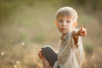 Cute, little, blond, boy, pointing a finger at nature. Close-up portrait. The concept of family, childhood. a place for a label