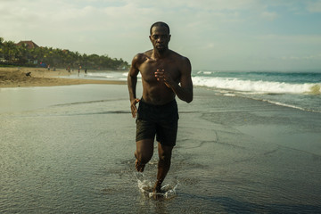 young attractive and fit black afro American man running on the beach doing Summer fitness jogging...