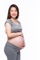 Happy asian pregnant woman smiling and touching her belly