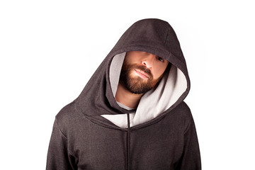 A man in a sports hood with an unshaven beard on a white background. A look from under the...