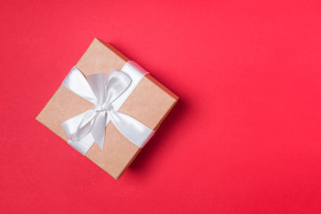 Giftbox with white ribbon on the red background