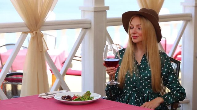 Beautiful young woman drinking wine in outdoor restaurant, space for text
