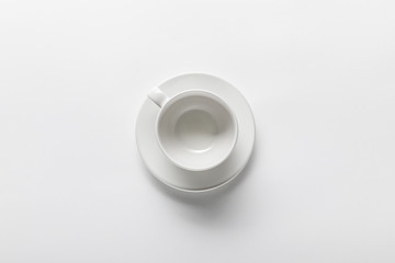 top view of empty white cup on saucer on white background
