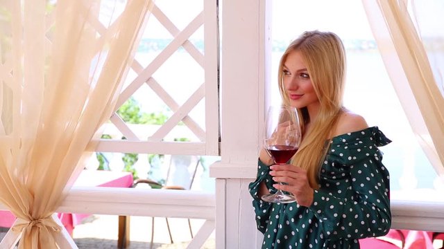 Beautiful young woman with glass of wine in outdoor restaurant, space for text