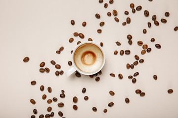 top view of coffee cup with foam on beige background with coffee grains