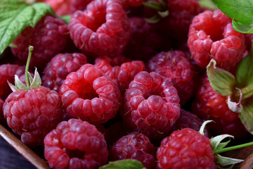 Fresh ripe raspberries in clay bowl against dark background