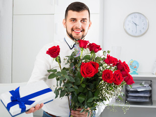 Man ready to present flowers and gift at holiday