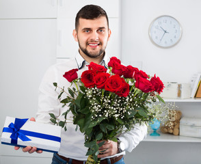 Man ready to present flowers and gift at holiday