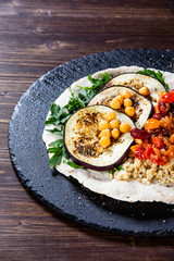 Groats with sauce and vegetables on tortilla