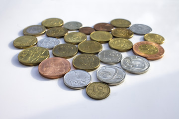  Coins of different countries laid out in the shape of a heart on a white background.