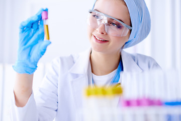 Woman holding test tube. Researcher is surrounded by medical vials and flasks