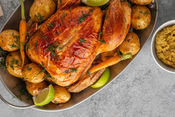 Chicken baked with potatoes, lime and herbs in grey pan. Top view.