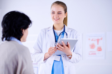 Fototapeta premium Doctor talking to a patient in a hospital and holding a tablet.