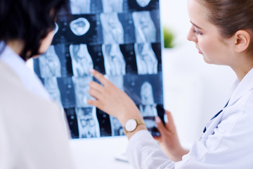 Female doctor shows patient Xray in medical office